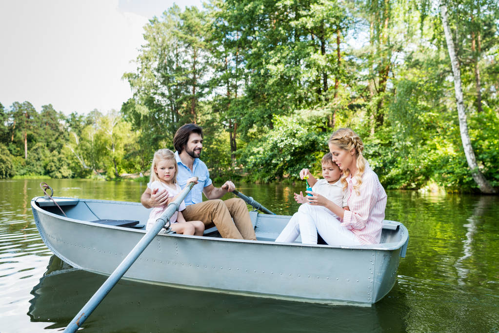 щаслива молода сім'я верхи на човні на річці в парку
 - Фото, зображення