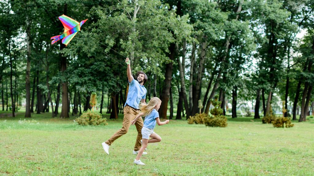 vue latérale du père et de la fille heureux courir avec cerf-volant au parc
 - Photo, image