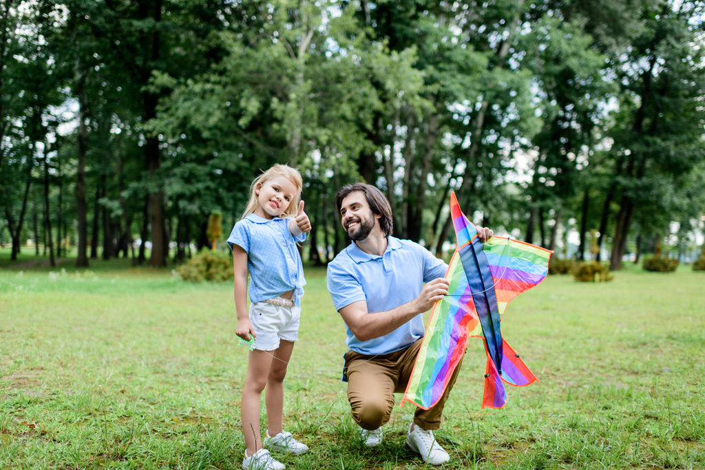 schöner glücklicher Vater mit Drachen und entzückender kleiner Tochter, die Zeit zusammen im Park verbringt - Foto, Bild