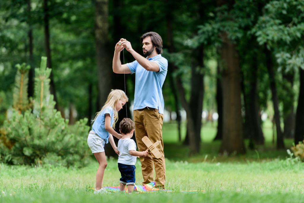 father and adorable little kids spending time together at park - Photo, Image