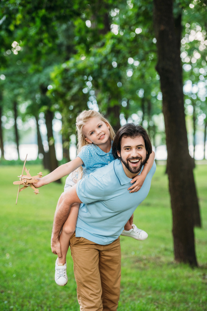 suloinen tytär reppuselkä onnellinen isä ja leikkii lelu kone puistossa
 - Valokuva, kuva