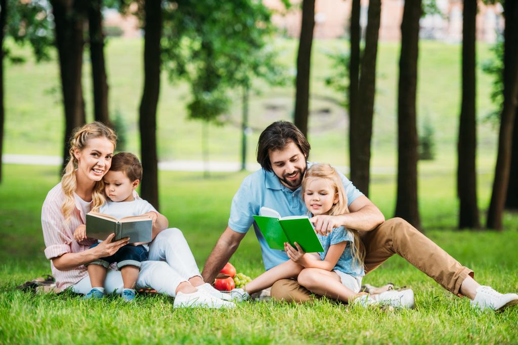 kaunis nuori perhe istuu nurmella puistossa ja lukeminen kirjoja
 - Valokuva, kuva