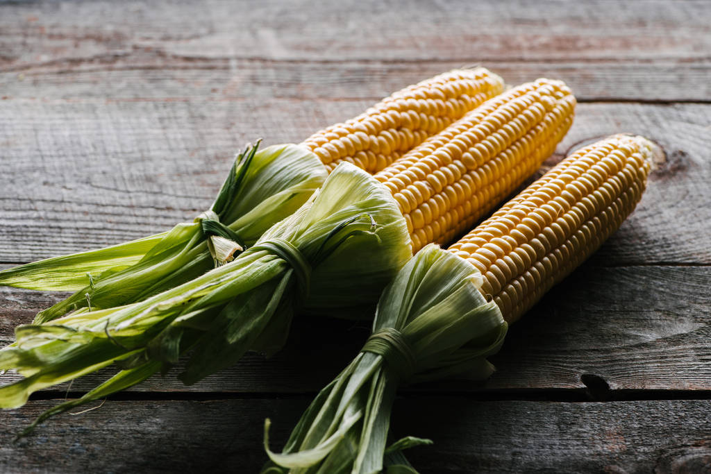 close up view of fresh ripe corn cobs arranged on wooden surface - Photo, Image