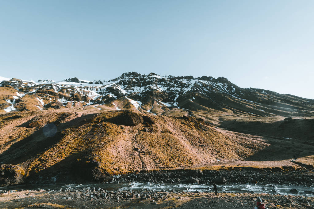 Piscina natural Seljavallalaug en iceland con el hombre en el agua y el clima nevado y las montañas de todo. Clima soleado y cielo azul
. - Foto, imagen