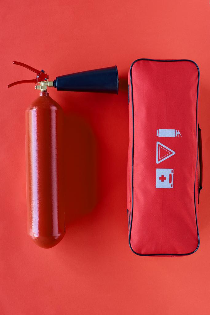 赤の背景に消火器と自動車用ハンドバッグのトップ ビュー - 写真・画像