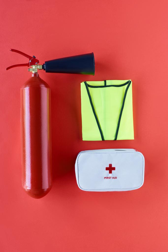 vista dall'alto dell'estintore, giubbotto riflettente e kit di pronto soccorso su sfondo rosso
 - Foto, immagini