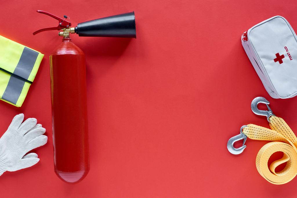 Yangın söndürücü, ilk yardım çantası ve kırmızı zemin üzerine Otomotiv aksesuarları ile düz lay - Fotoğraf, Görsel