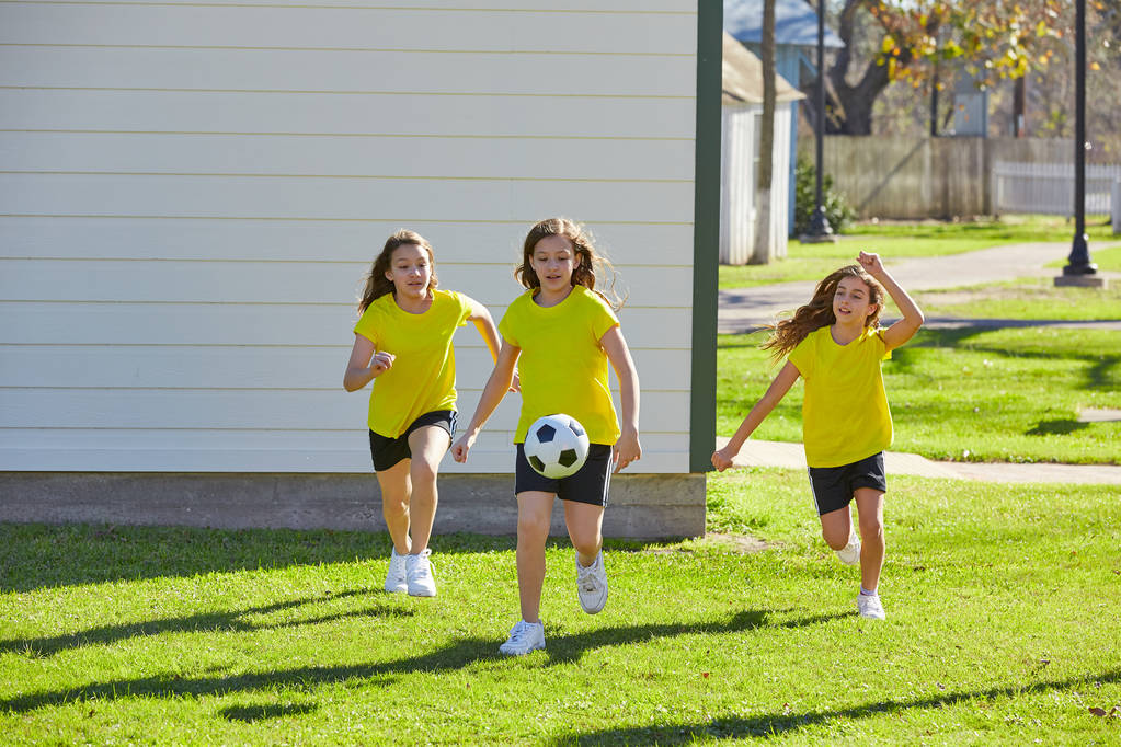 Подростки-подружки играют в футбол на траве в парке
 - Фото, изображение