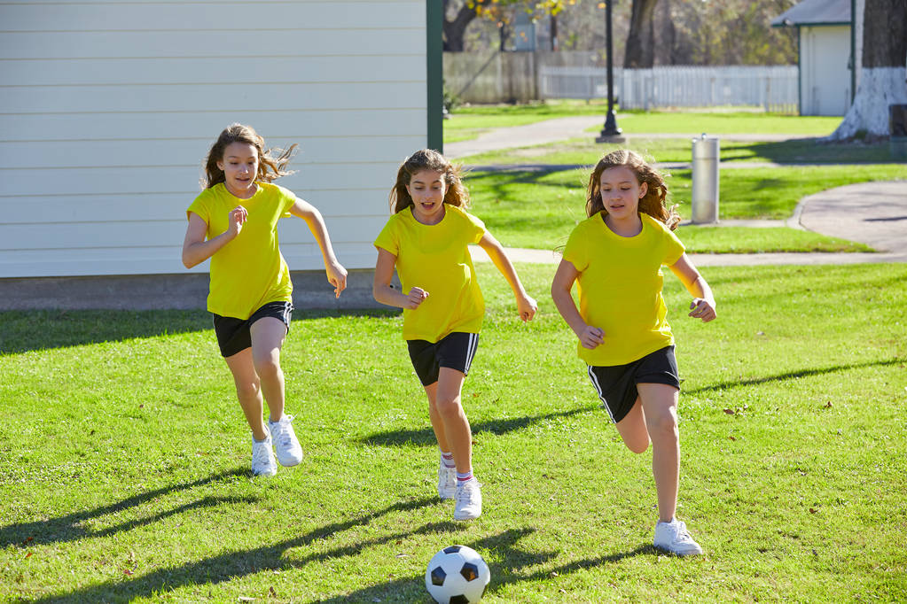 Подростки-подружки играют в футбол на траве в парке
 - Фото, изображение