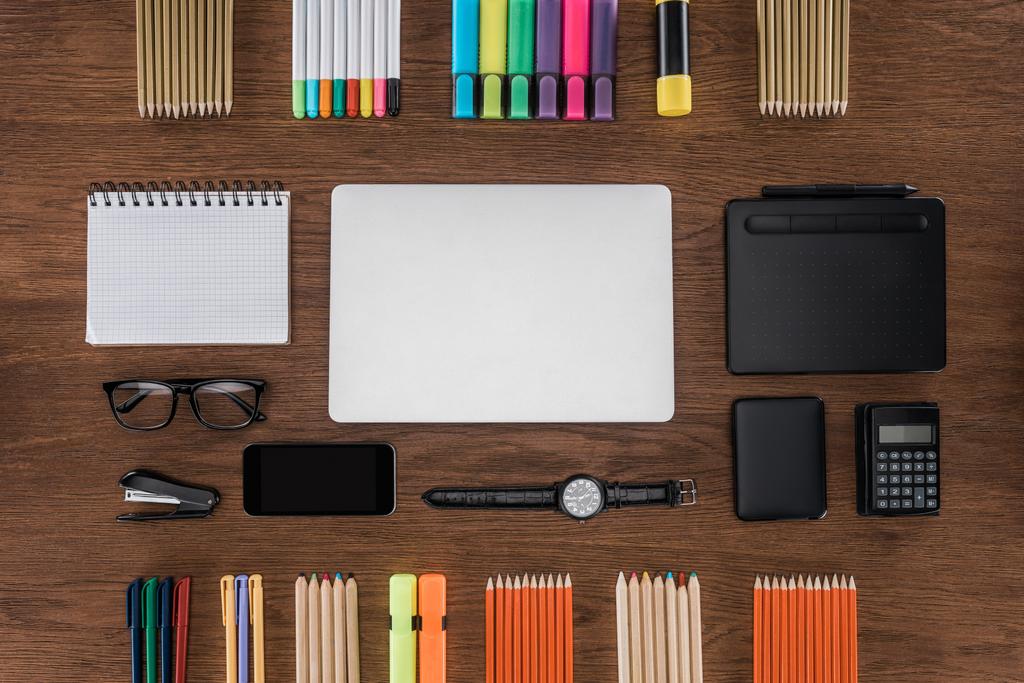 pohled shora pracoviště s uspořádány laptop, smartphone, Kalkulačka a barevné tužky na dřevěný stůl  - Fotografie, Obrázek