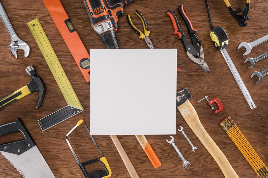 vista superior de papel vazio perto arranjado várias ferramentas na mesa de madeira
 - Foto, Imagem