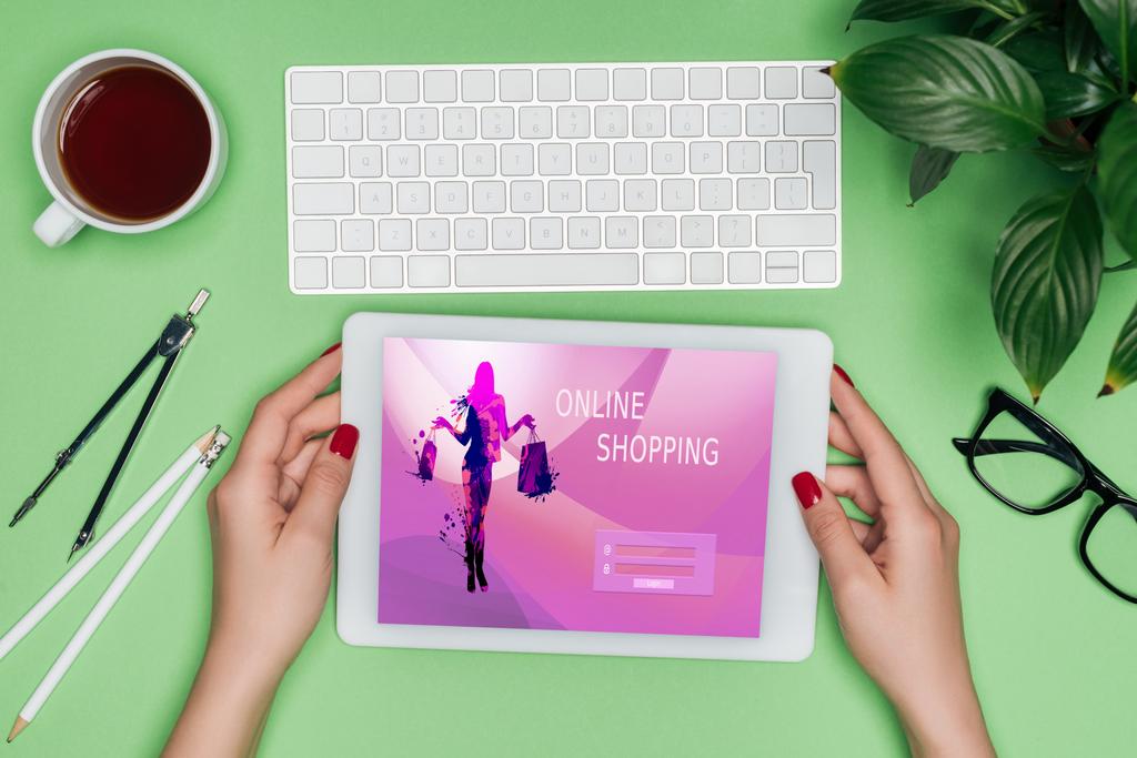 oříznutý obraz žen architekta drží digitální tablet s on-line nakupování na obrazovce u stolu s rozdělovačem, kávy a v květináči  - Fotografie, Obrázek