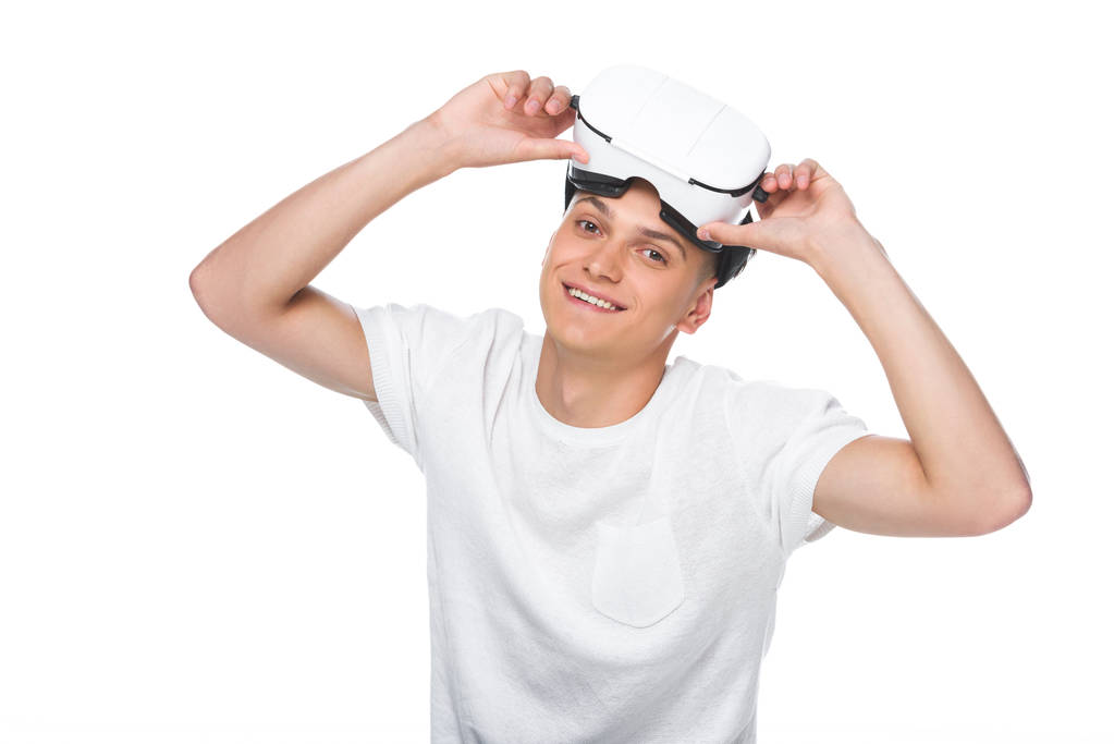 Beyaz tişörtlü beyaz izole sanal gerçeklik kulaklık giyen gülümseyen yakışıklı adam - Fotoğraf, Görsel