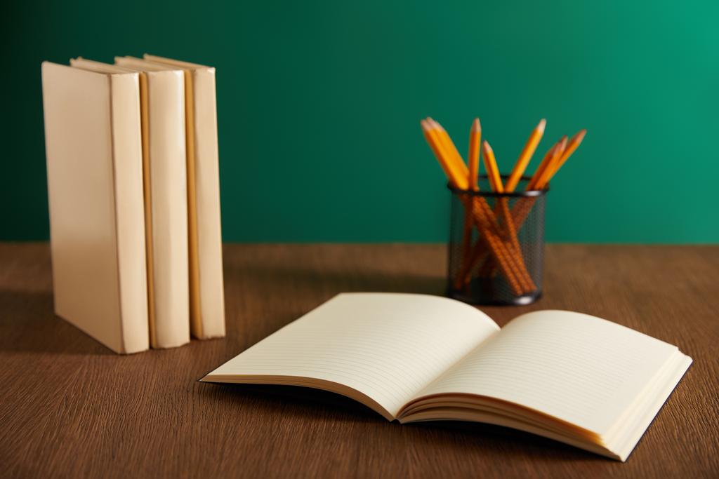 Aufgeschlagenes Lehrbuch, Bücher und Bleistifte auf Holztisch - Foto, Bild