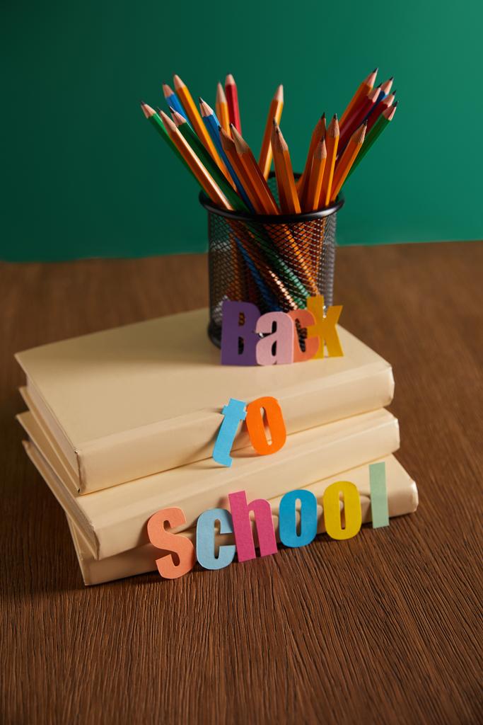 Bleistifte und Bücher auf Holztisch mit Schulschriftzug - Foto, Bild