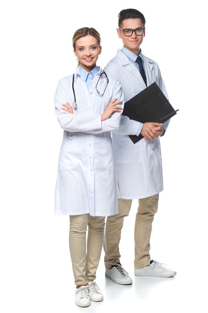 врачи, стоящие со стетоскопом и планшетом, смотрят на камеру, изолированную на белом
 - Фото, изображение