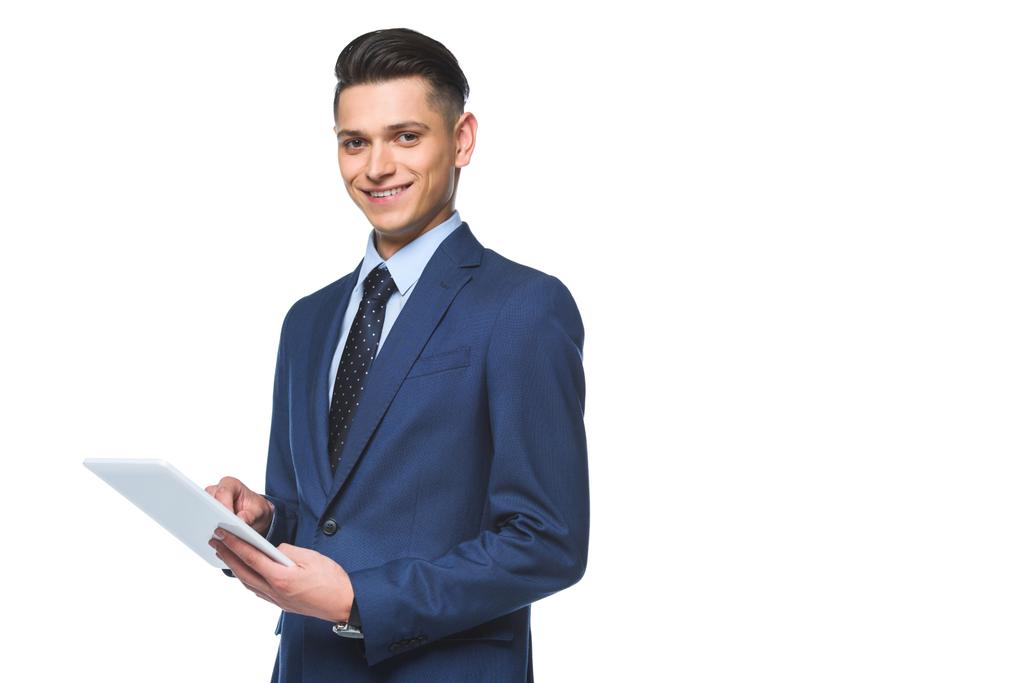 glücklicher junger Geschäftsmann in stylischer blauer Jacke mit Tablet und Blick auf Kamera isoliert auf weiß - Foto, Bild