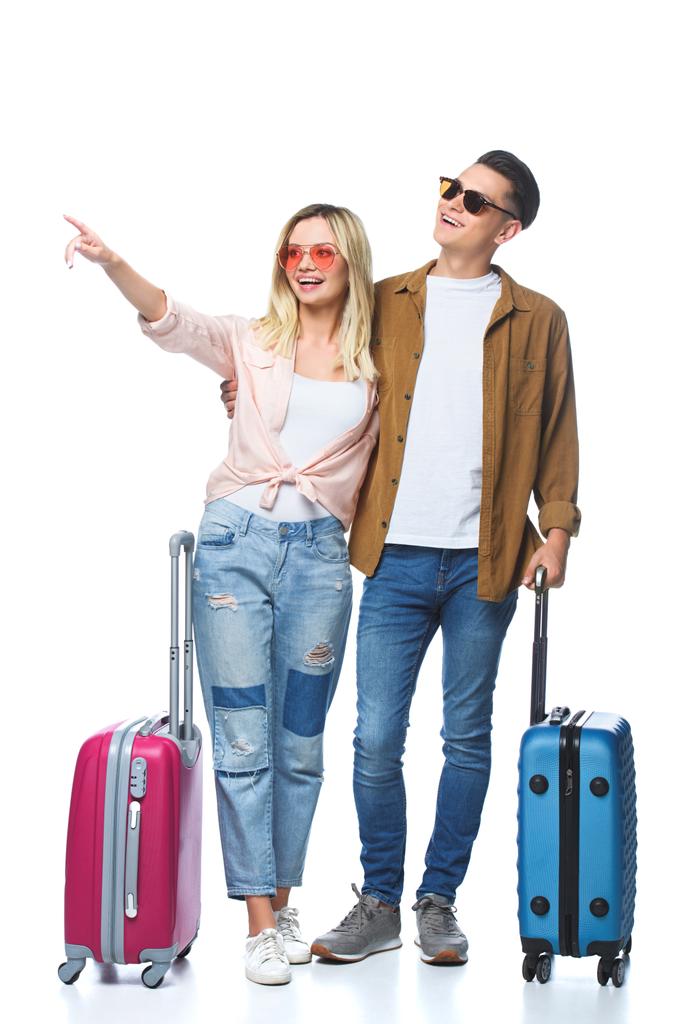 junges reisendes Paar mit Koffern, die irgendwo isoliert auf weiß zeigen - Foto, Bild