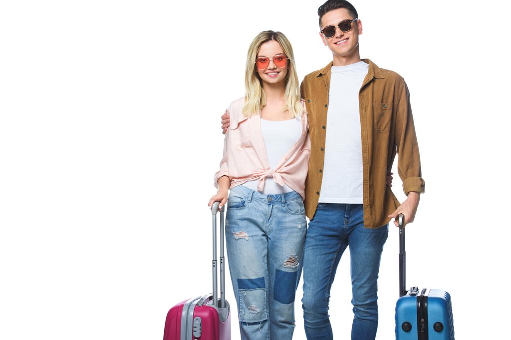 junges lächelndes Paar mit Koffern, das isoliert auf weiß in die Kamera blickt - Foto, Bild