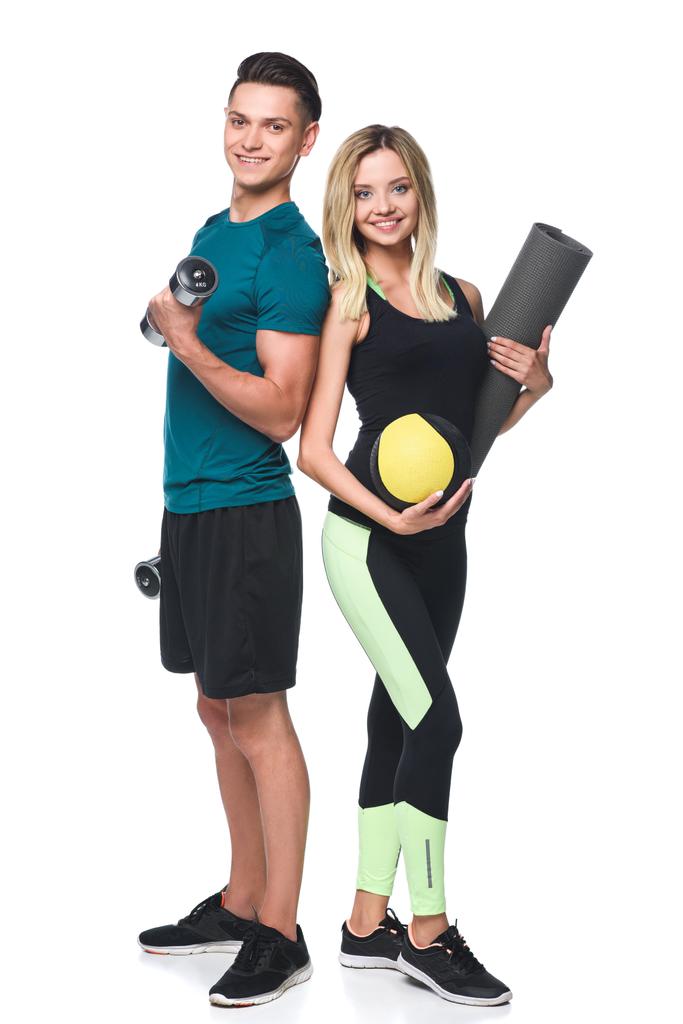 молода спортивна пара з різноманітним обладнанням дивиться на камеру ізольовано на білому
 - Фото, зображення