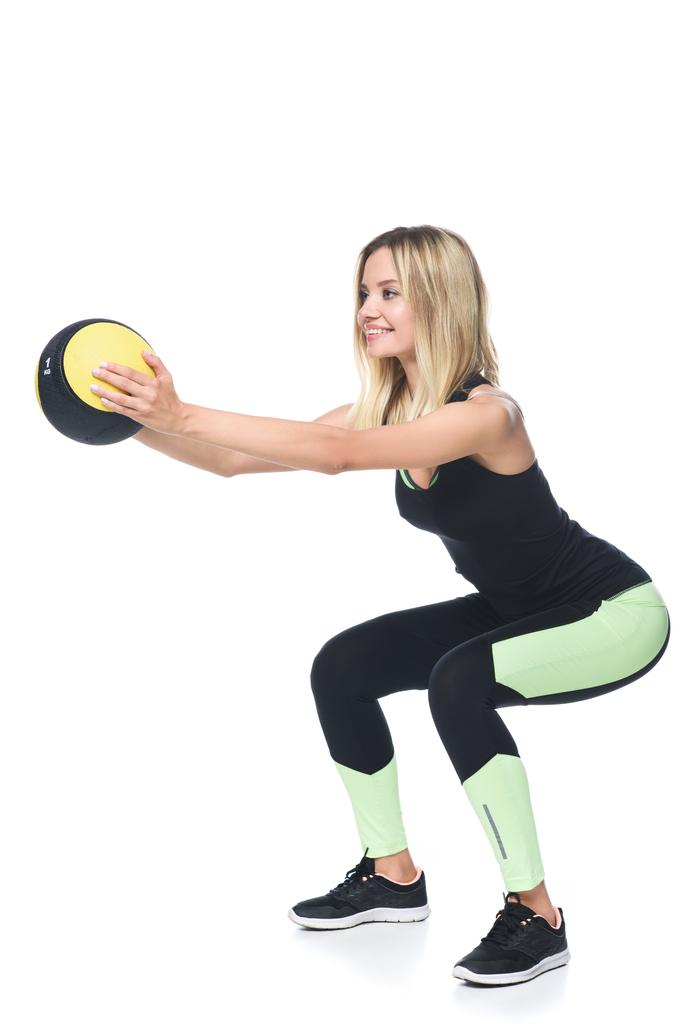 sportieve jonge vrouw doen squats met medicijnbal geïsoleerd op wit - Foto, afbeelding