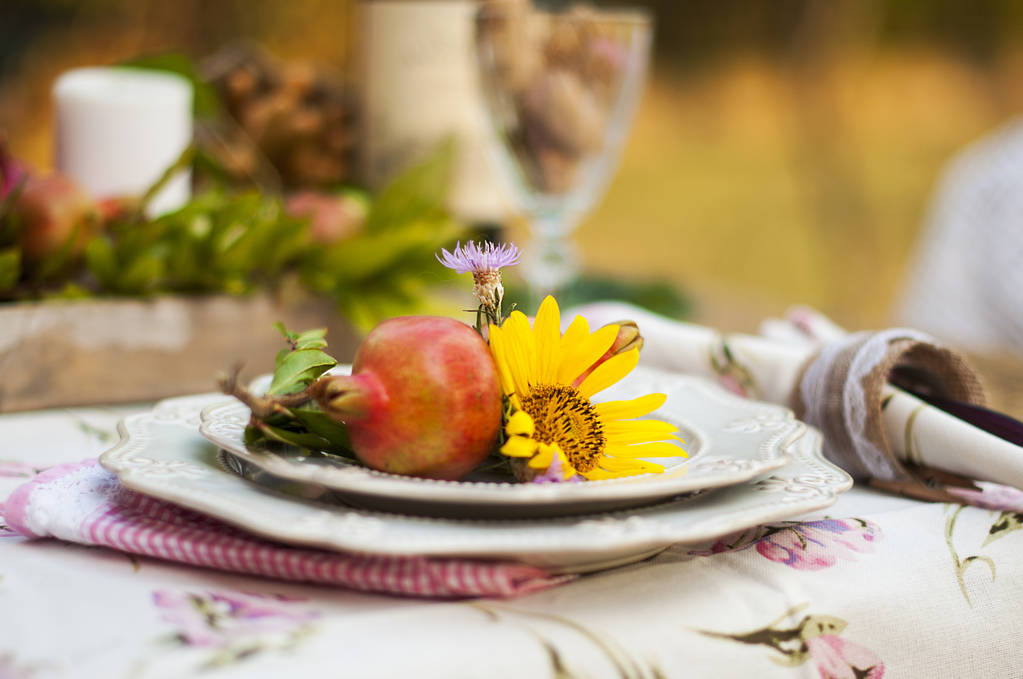 Cena romantica nel giardino autunnale, tavola apparecchiata per una bella cena. Vino, frutta, melograno e fiori. Picnic all'aria aperta
. - Foto, immagini