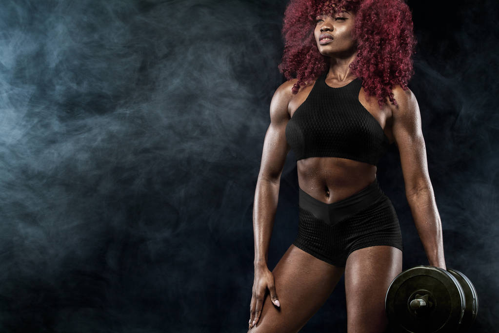 Sporty bella donna con manubri rende fitness esercizio su sfondo nero per rimanere in forma
 - Foto, immagini
