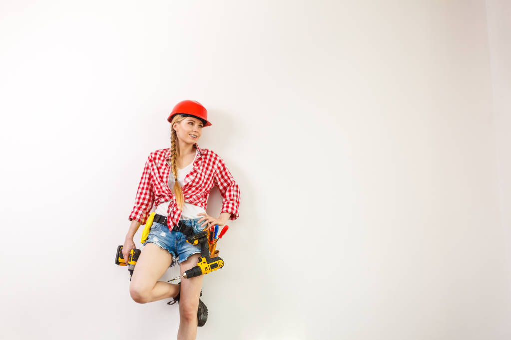 Mujer usando casco usando taladro. Chica trabajando en remodelación plana. Construcción, reparación y renovación. - Foto, imagen