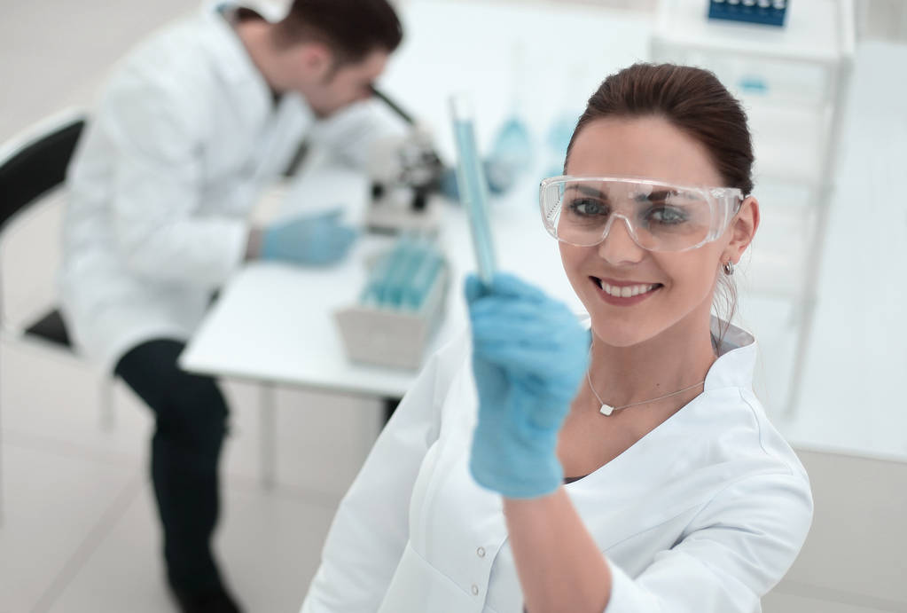 mujer científica sonriente mirando el tubo con los resultados del análisis
 - Foto, imagen