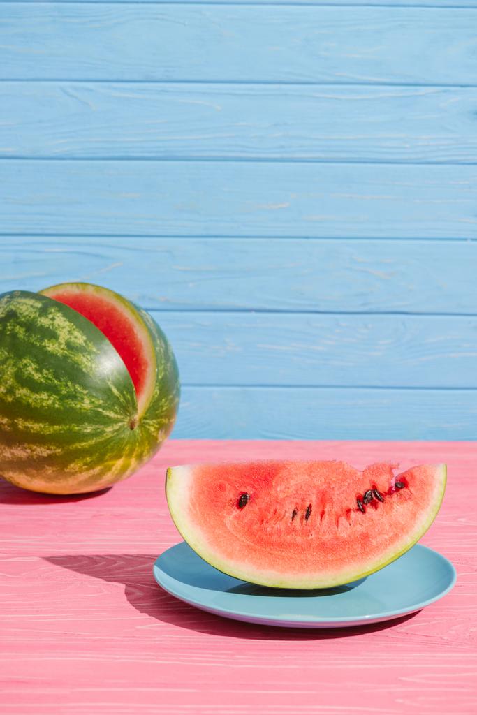 Close-up van verse watermeloen op roze tafelblad op blauwe achtergrond - Foto, afbeelding
