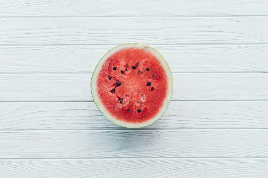 Draufsicht auf frische Wassermelone zur Hälfte auf weiße Holztischplatte - Foto, Bild