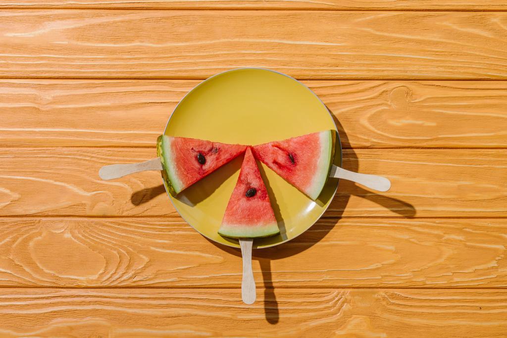 flat lay with watermelons on ice cream sticks on plate on wooden tabletop - Photo, Image