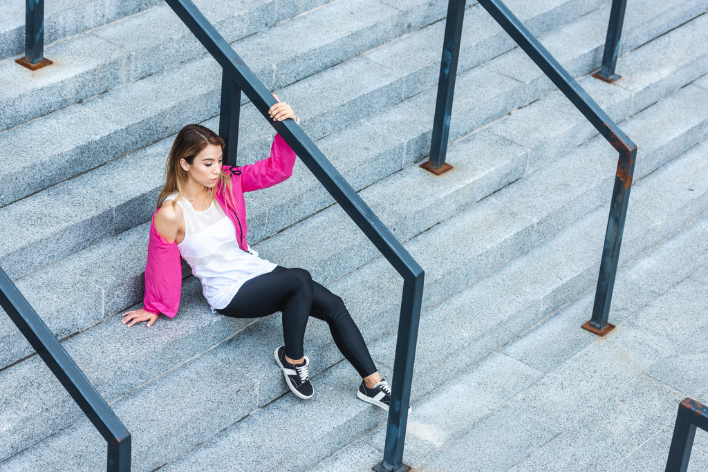 high angle view of stylish asian woman sitting on stairs at urban street - Photo, Image
