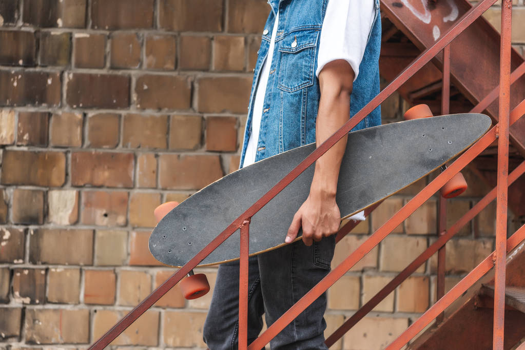 image recadrée de l'homme élégant tenant skateboard à la rue urbaine
 - Photo, image