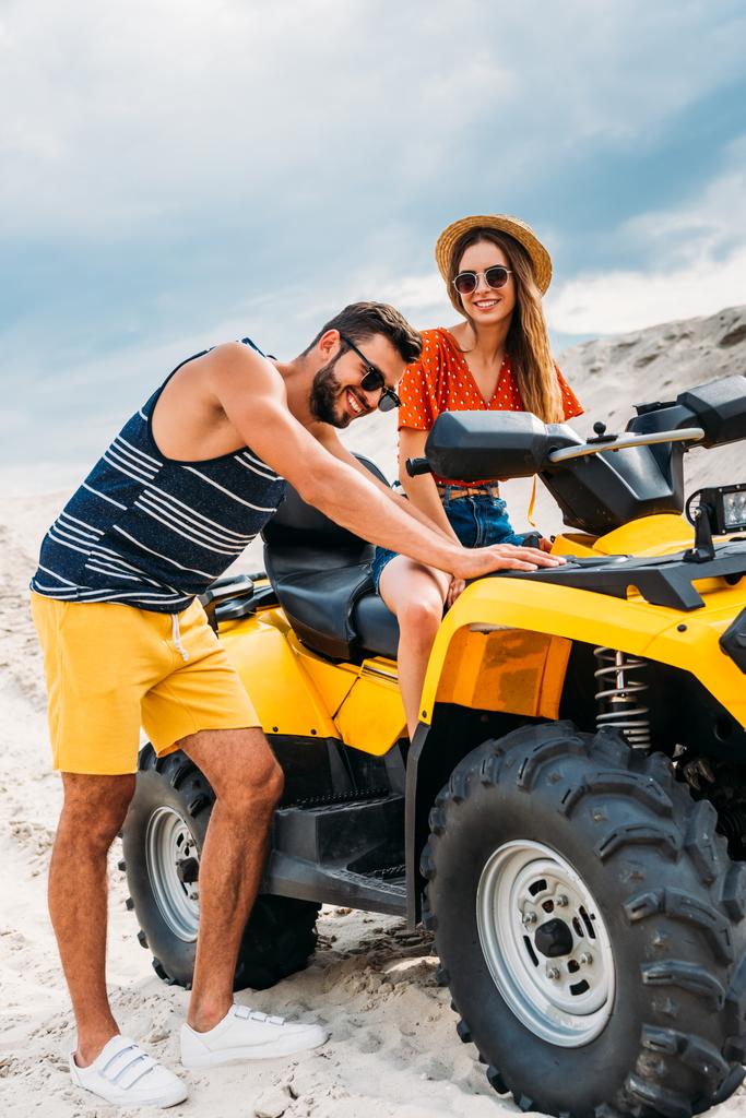 handsome young man pushing atv with his girlfriend got stuck in desert - Photo, Image