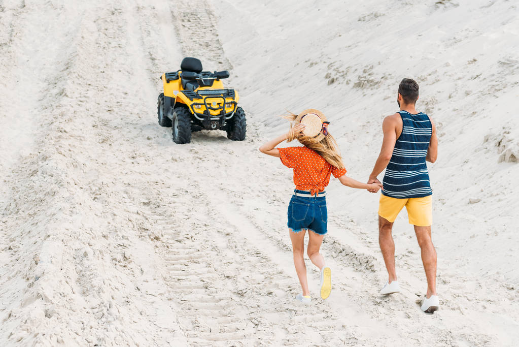 vista posteriore della giovane coppia che va a ATV da dune sabbiose
 - Foto, immagini