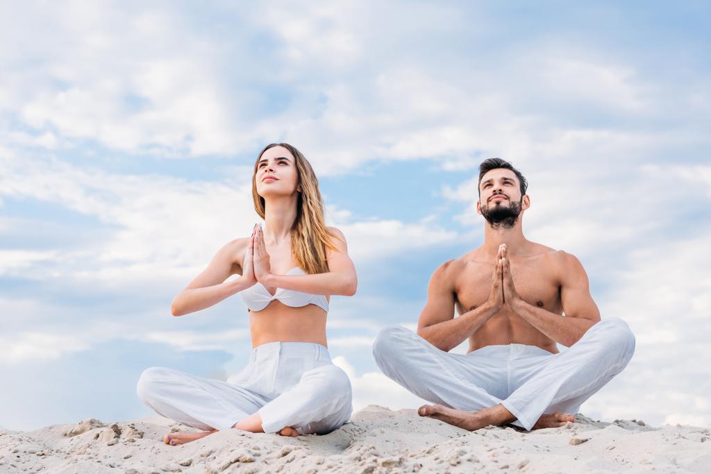 fittes junges Paar meditiert auf Sanddüne in Lotus-Pose - Foto, Bild