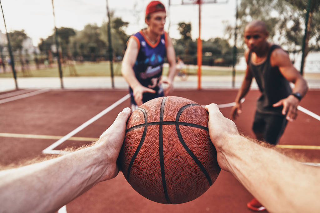 zbliżenie na mężczyznę trzymającego piłkę podczas gry w koszykówkę z przyjaciółmi na zewnątrz - Zdjęcie, obraz