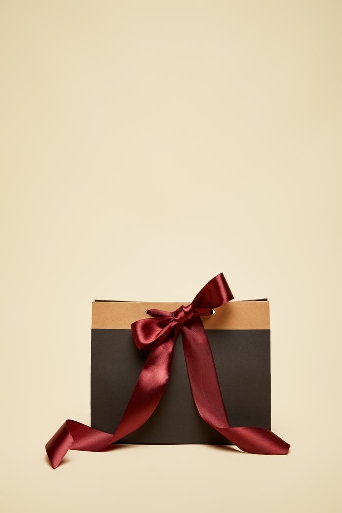 Módní černé nákupní taška s bordó mašlí izolované na béžové - Fotografie, Obrázek
