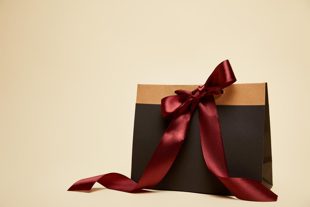 fashionable shopping bag with burgundy bow isolated on beige - Photo, Image