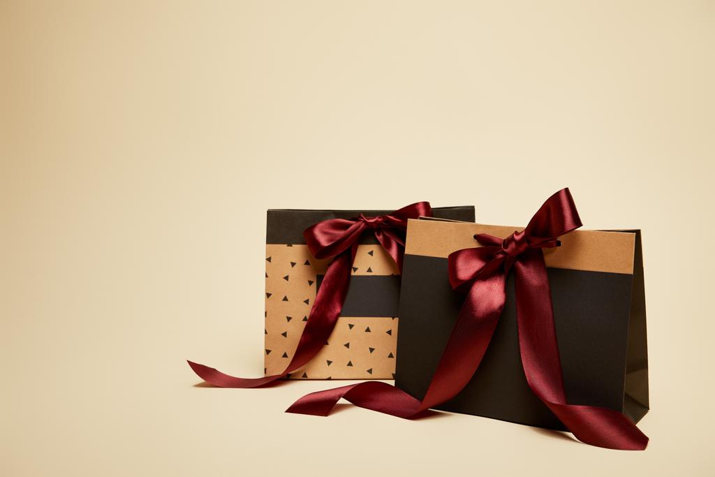 paper brown and black shopping bags with bows isolated on beige  - Photo, Image