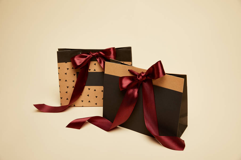 fashionable shopping bags with burgundy bows isolated on beige - Photo, Image