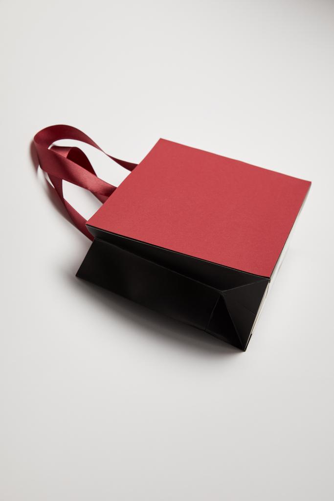 una bolsa de compras de color burdeos en superficie blanca
 - Foto, Imagen
