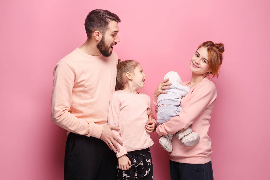Überraschte junge Familie blickt in Kamera auf rosa - Foto, Bild