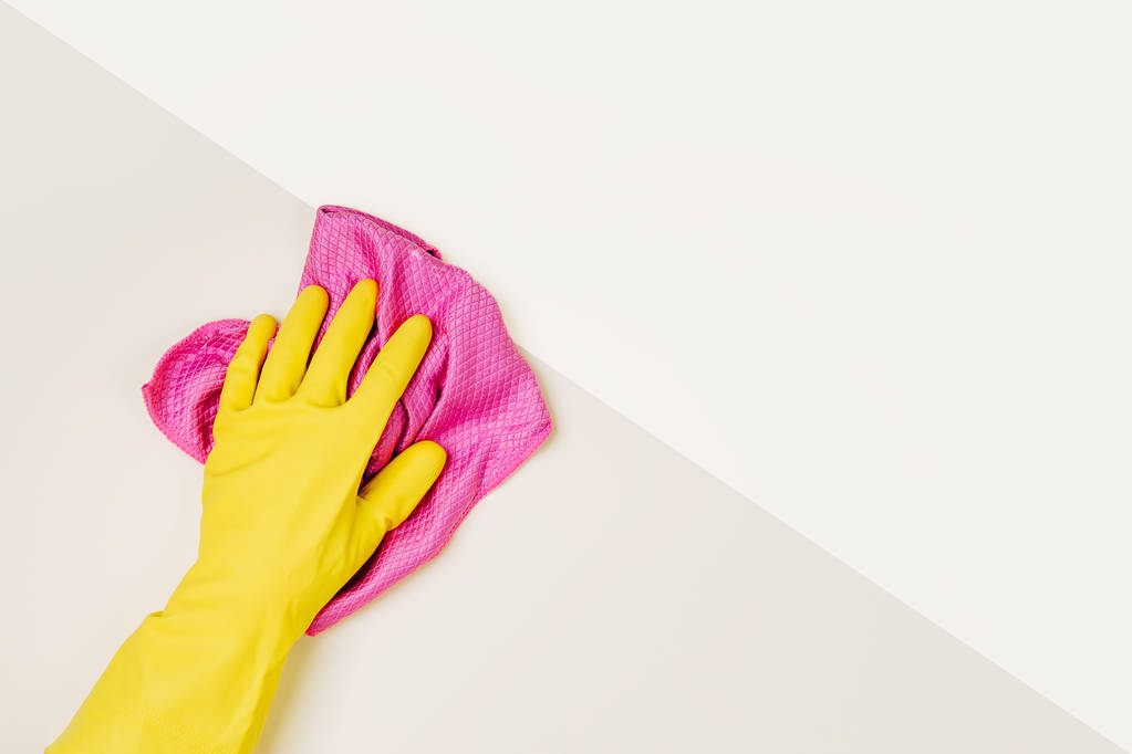 Nainen käsi puhdistus vaalean vaaleanpunainen tausta. Siivous- tai siivouskonseptin tausta. Kopioi tilaa. Tasainen, ylhäältä näkymä
. - Valokuva, kuva