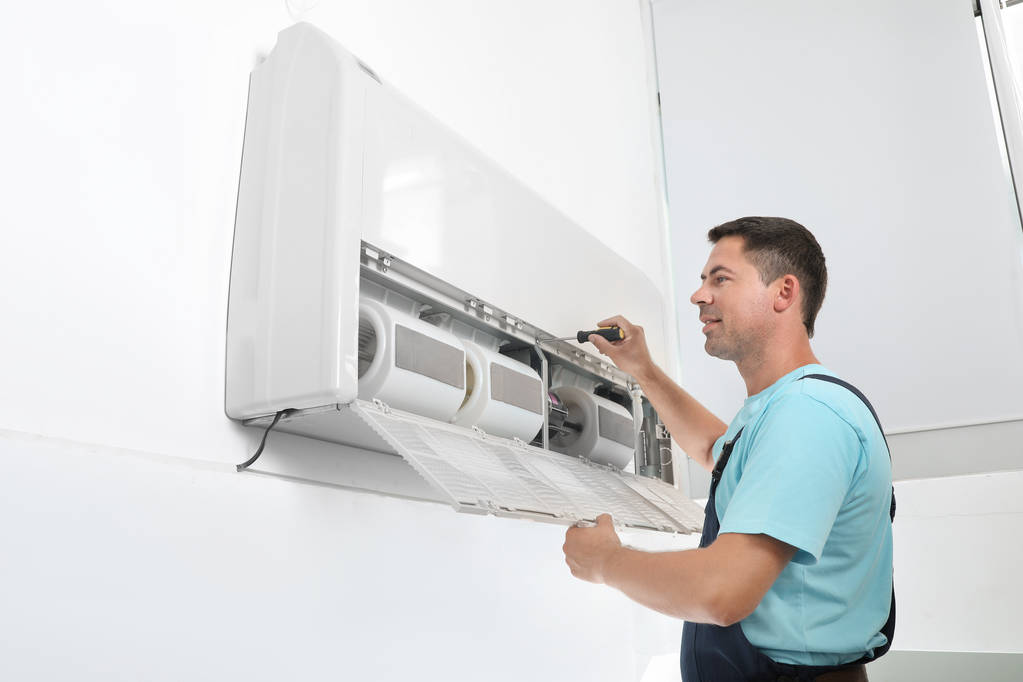 Técnico masculino que fija el aire acondicionado moderno en interiores
 - Foto, imagen