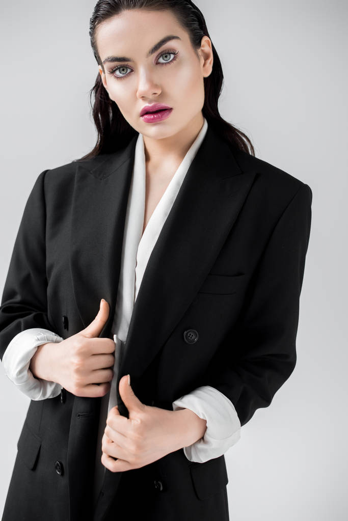 mooie elegante vrouw poseren in zwarte modieuze jas, geïsoleerd op grijs - Foto, afbeelding