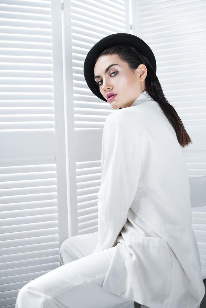ελκυστική νεαρή γυναίκα θέτοντας το μπερέ και λευκό μοντέρνο σακάκι - Φωτογραφία, εικόνα