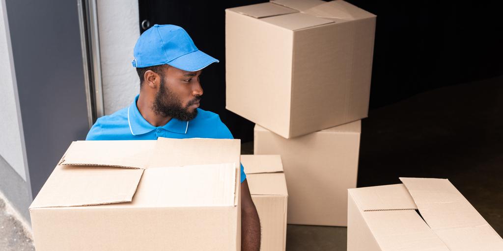 Africano americano entrega homem segurando caixa perto de armazenamento
 - Foto, Imagem