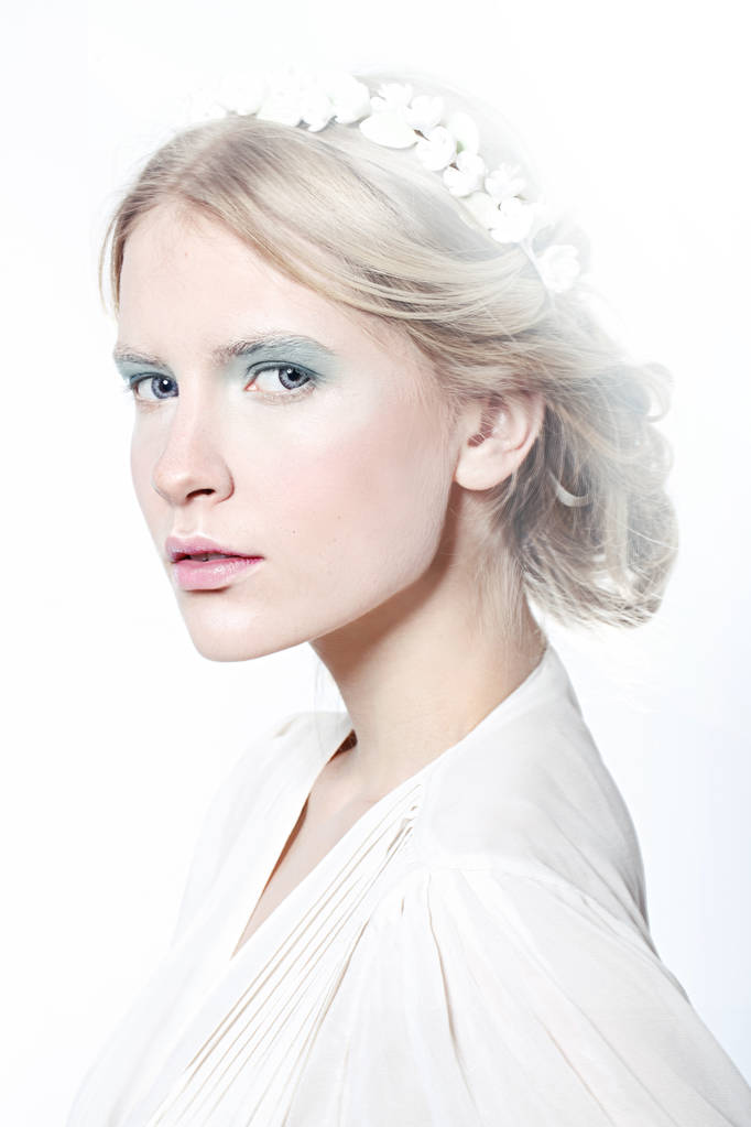 Красивая модель блондинка с голубыми тенями для век и розовыми губами в венке, позирующем изолированно на белом
  - Фото, изображение